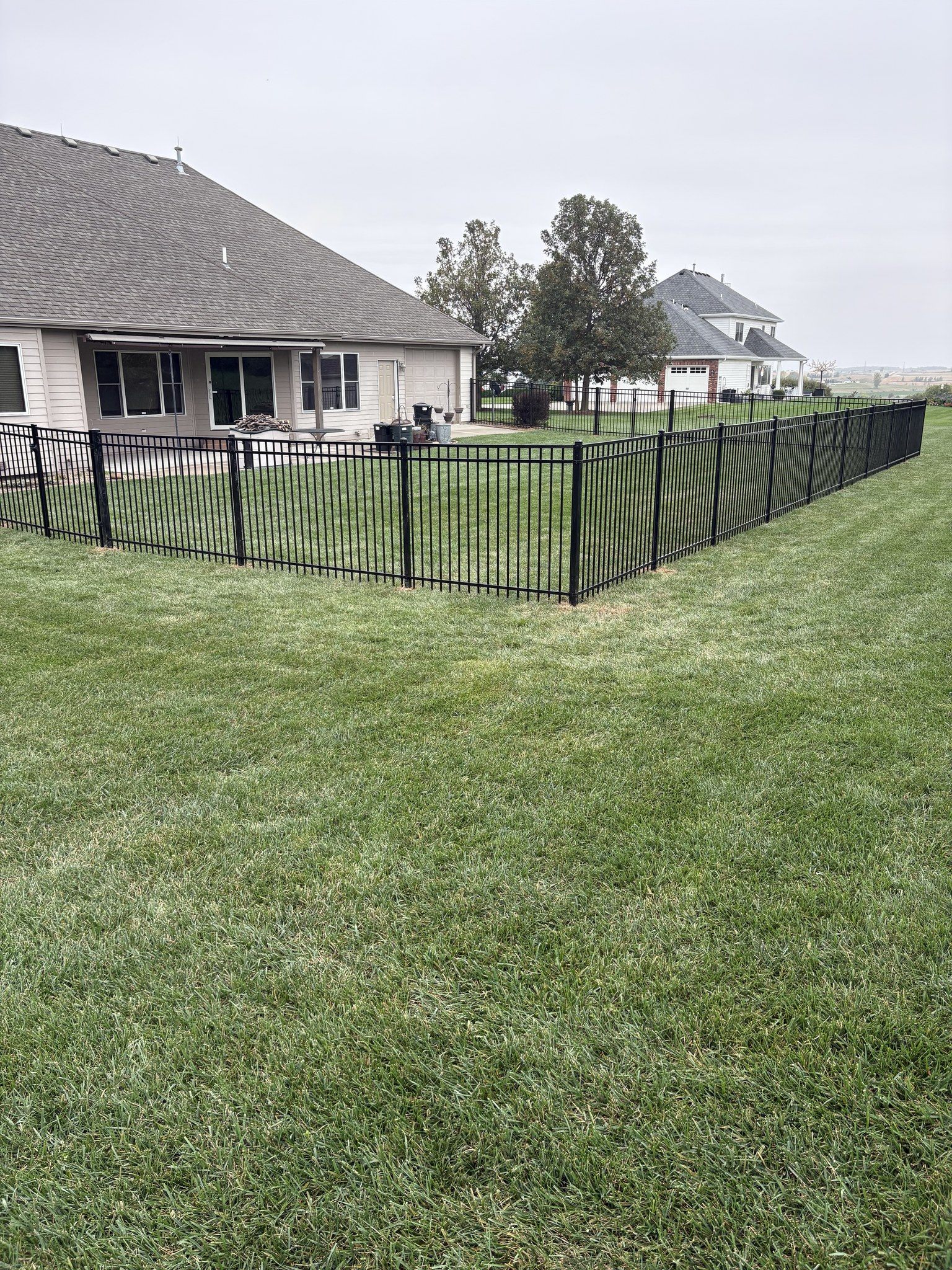 Black ornamental metal fence with green privacy slats around residential property