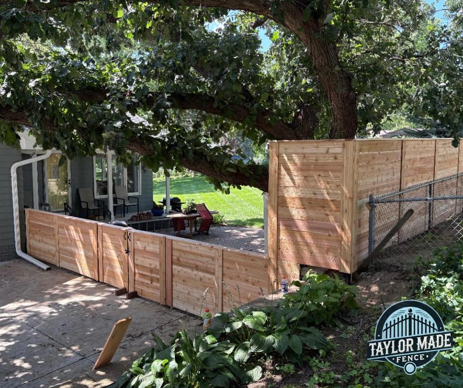 Custom horizontal cedar fence with gate and black metal posts in backyard